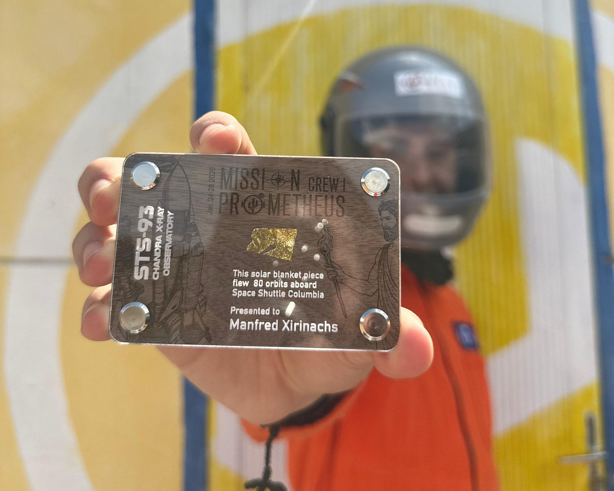 Analog astronaut holding a personalized Mission Prometheus crew card with a flown STS-93 solar blanket fragment