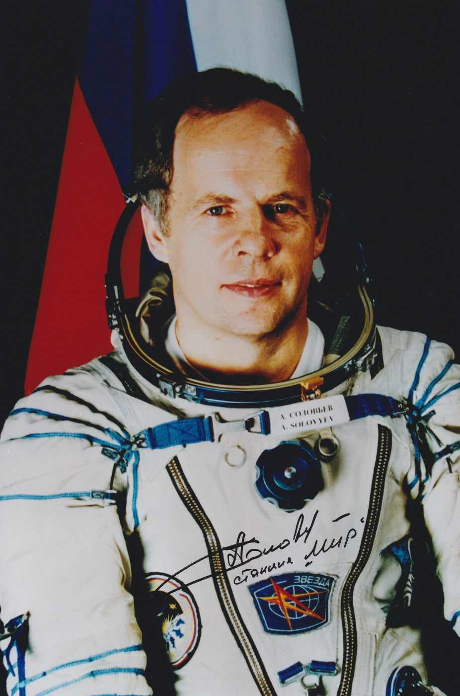 Signed portrait of cosmonaut Anatoly Solovyev in Sokol spacesuit with mission patch and autograph, perfect for space memorabilia collectors