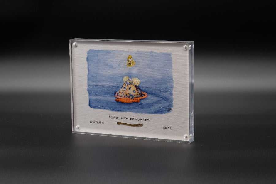 Vertical acrylic display with a watercolor of the Apollo capsule splashdown and an embedded flown spacecraft fragment beneath the artwork.