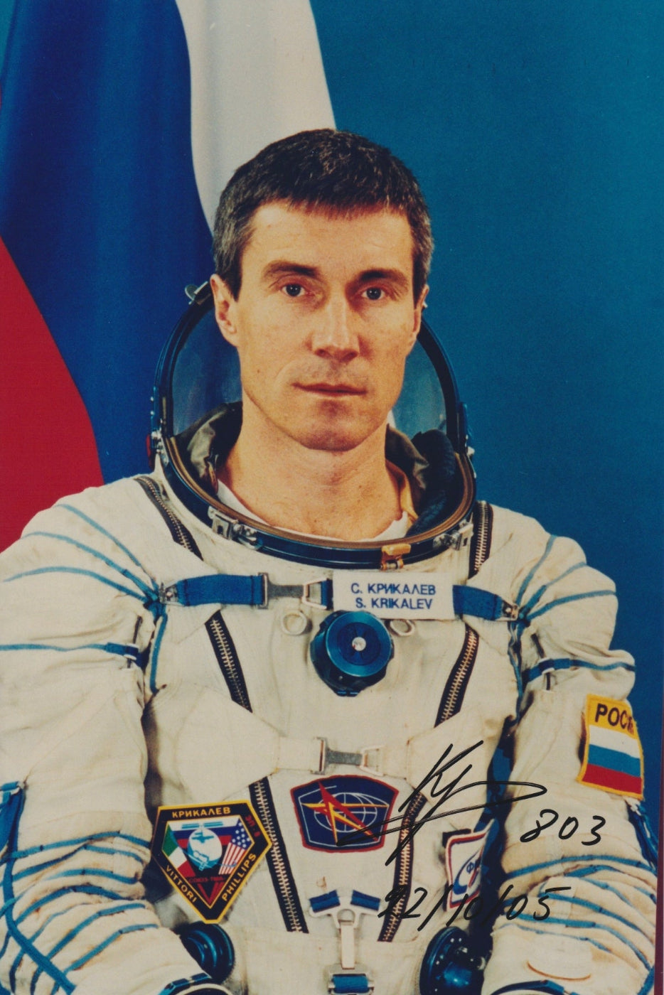 Signed portrait of cosmonaut Sergei Krikalev in Sokol spacesuit with mission patches, ideal for space memorabilia collectors