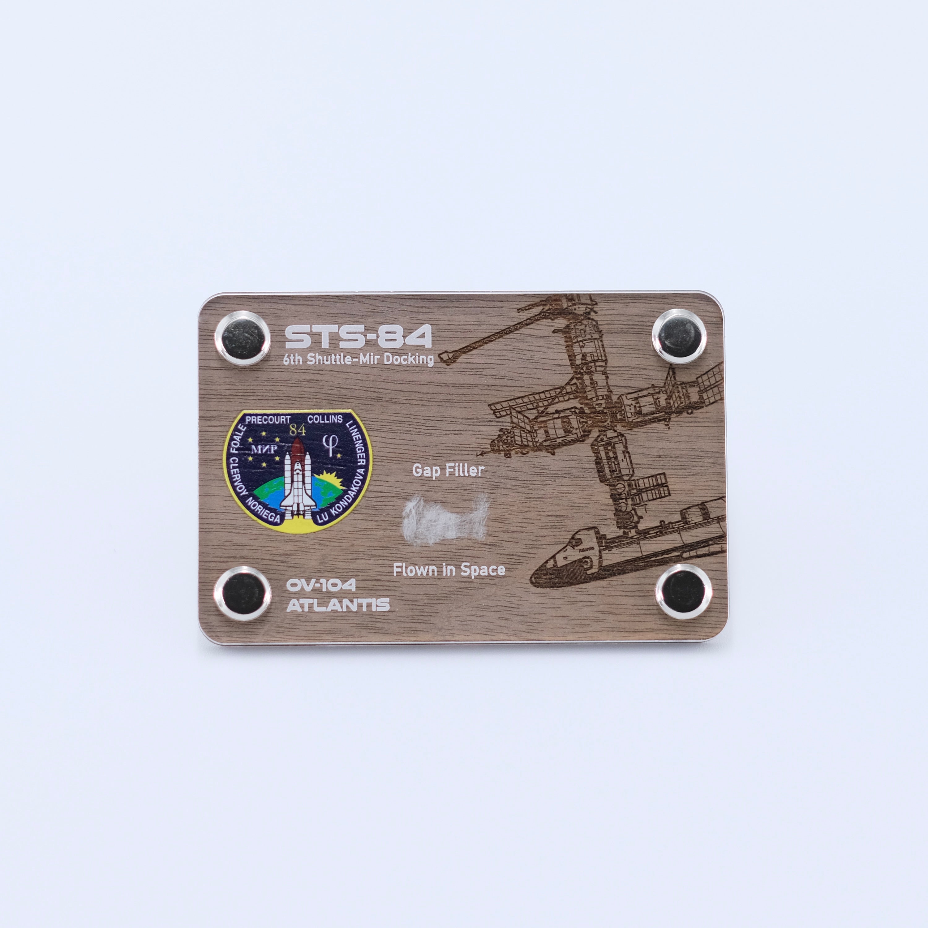 Authentic flown gap filler artifact from Space Shuttle Atlantis STS-84, the sixth Shuttle-Mir docking mission, displayed in a handcrafted collectible card.