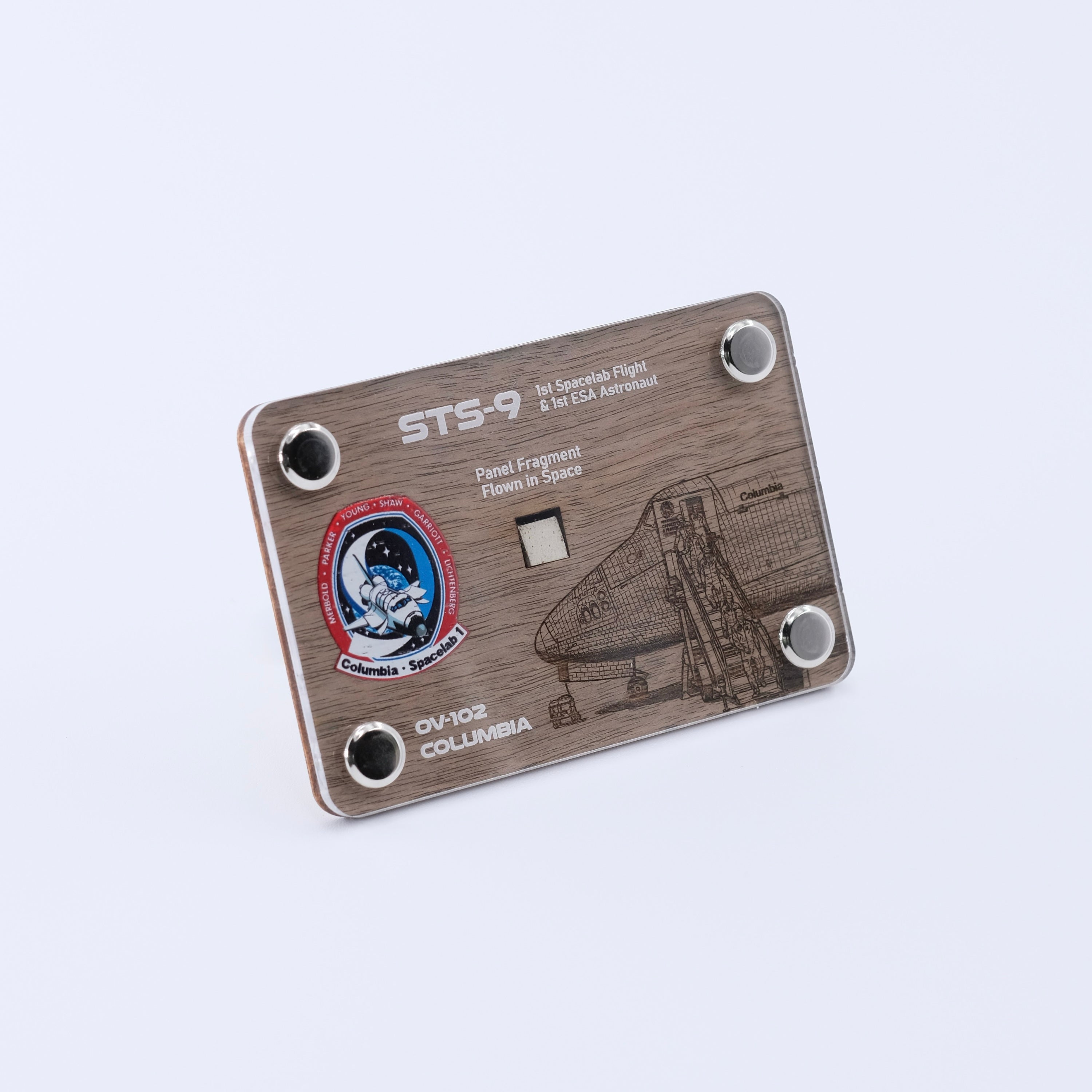 Angled view of an authentic flown panel fragment artifact display card from Space Shuttle Columbia STS-9, the first Spacelab mission and first flight of an ESA astronaut.