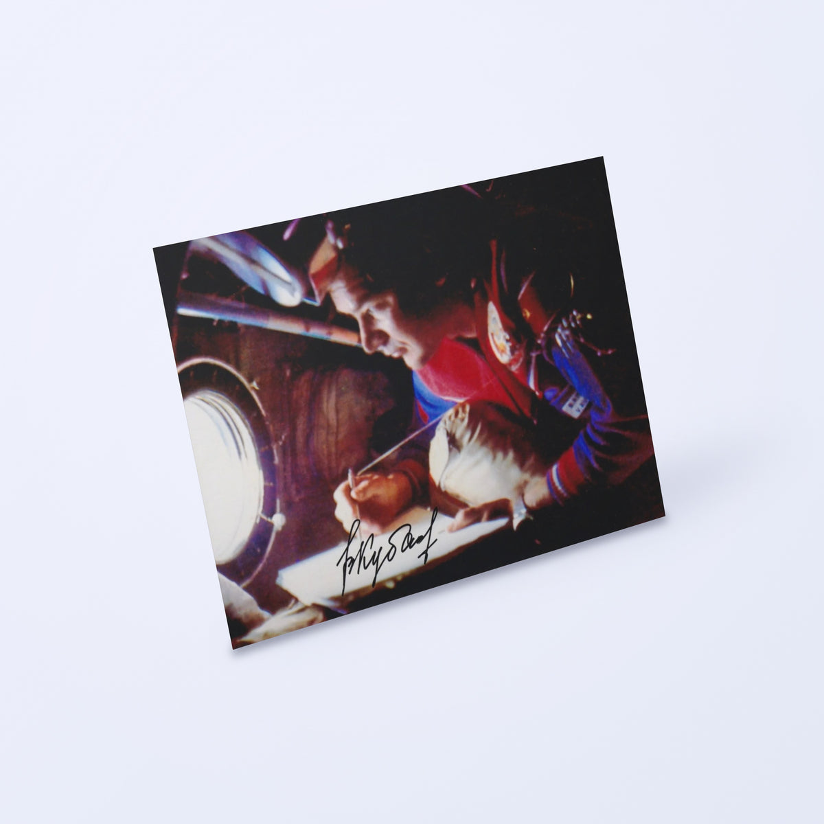 Signed photo of cosmonaut Valery Kubasov at a Soyuz spacecraft window, shown at an angle on a light background
