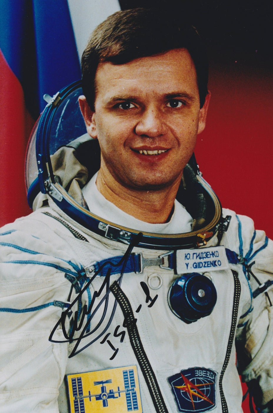 Signed portrait of cosmonaut Yuri Gidzenko in Sokol spacesuit with mission patches, ideal for space memorabilia collectors