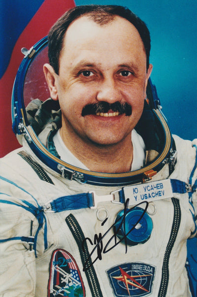 Signed portrait of Mir cosmonaut Yuri Usachev in Sokol spacesuit with name tag and mission patches.
