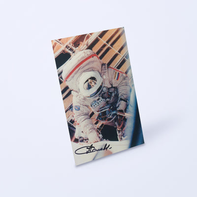 Signed photo of cosmonaut Anatoly Solovyev in an Orlan EVA spacesuit, shown at an angle on a light background