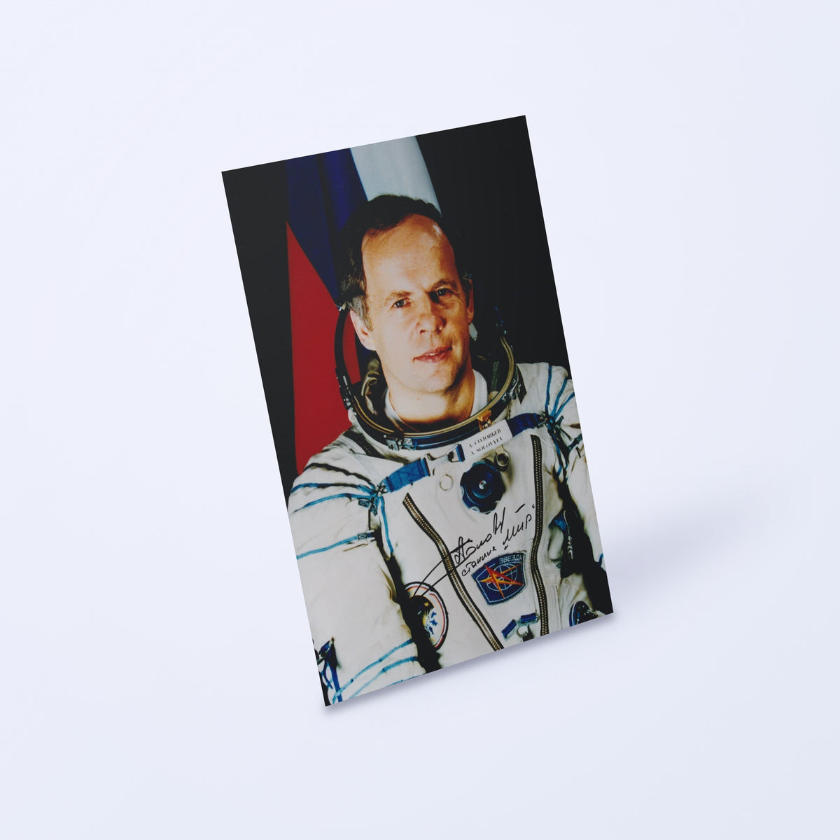 Signed portrait of cosmonaut Anatoly Solovyev in a Sokol spacesuit, shown at an angle on a light background