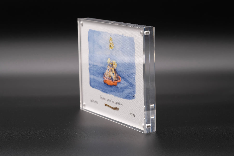 Vertical acrylic display with a watercolor of the Apollo capsule splashdown and an embedded flown spacecraft fragment beneath the artwork.