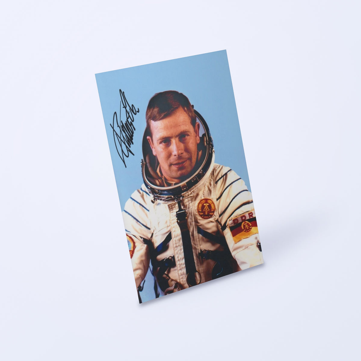 Signed portrait of GDR reserve cosmonaut Eberhard Köllner in a Sokol spacesuit, shown at an angle on a light background