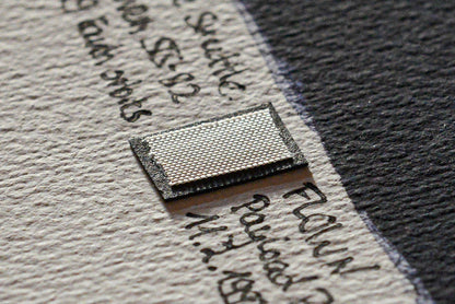 Close-up photo of a flown Space Shuttle Discovery STS-82 payload bay liner fragment mounted on an artwork card by The New Space Age