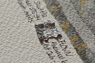 Close-up of a flown STS-94 Columbia thermal blanket fragment mounted on an artwork card by The New Space Age