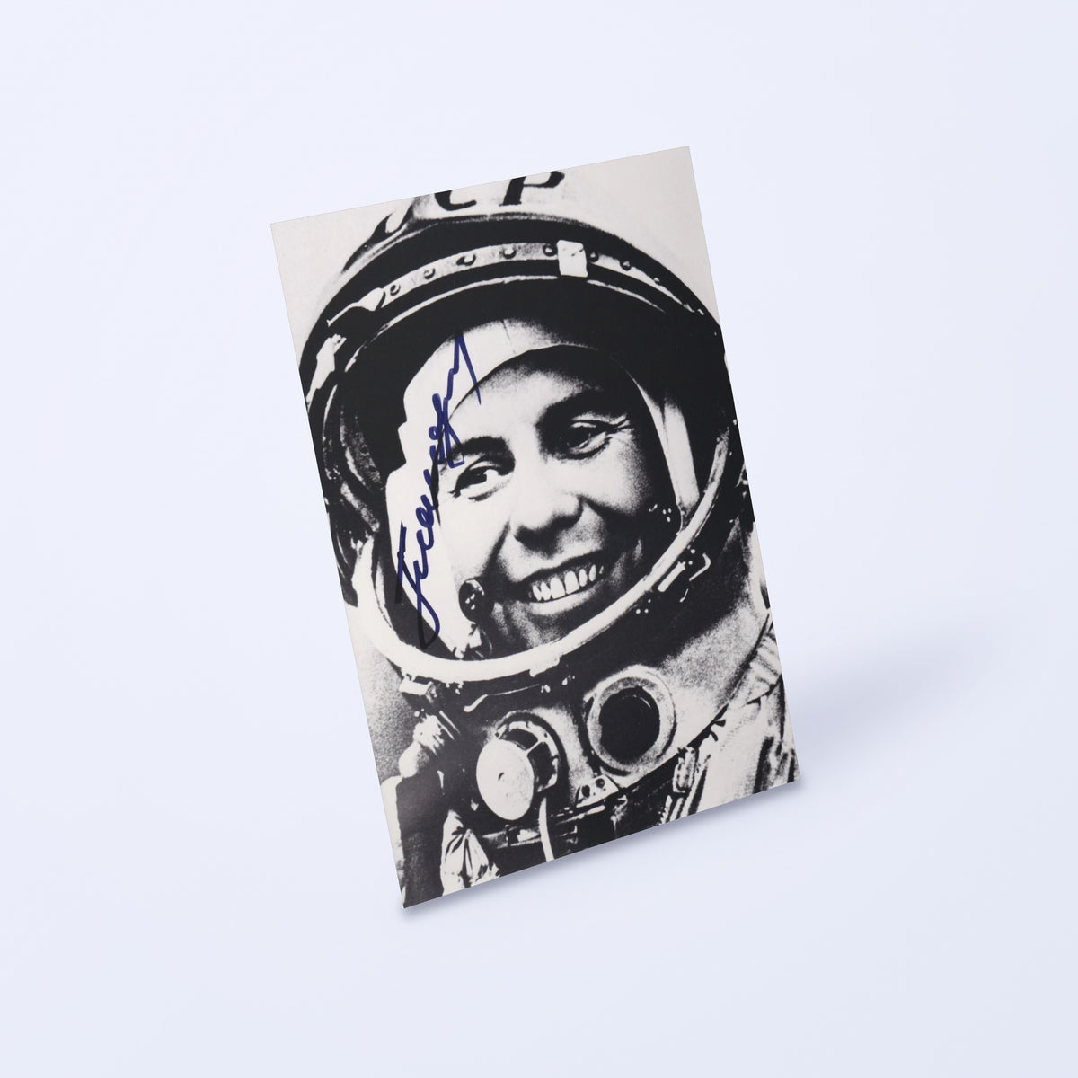 Signed black-and-white portrait of cosmonaut Pavel Popovich with CCCP helmet, shown at an angle on a light background