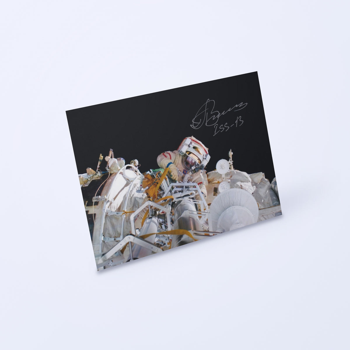 Signed photo of cosmonaut Pavel Vinogradov during an ISS-13 spacewalk, shown at an angle on a light background