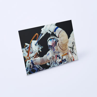Signed photo of cosmonaut Sergey Treshchov in an Orlan spacesuit during a spacewalk, shown at an angle on a light background