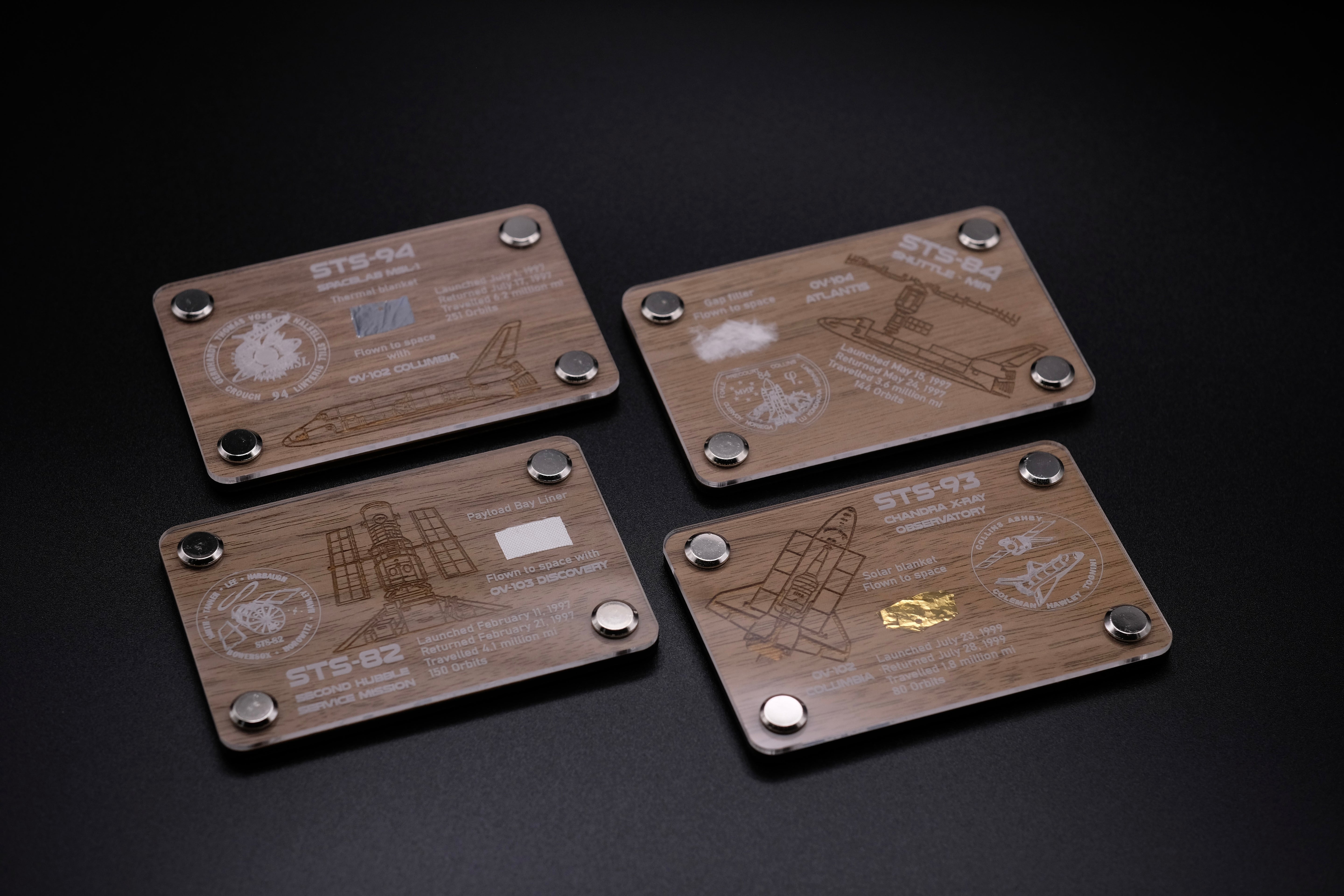 Collection of premium wooden displays featuring flown fragments from Space Shuttle missions STS-82, STS-84, STS-93, and STS-94, each with engraved mission details.