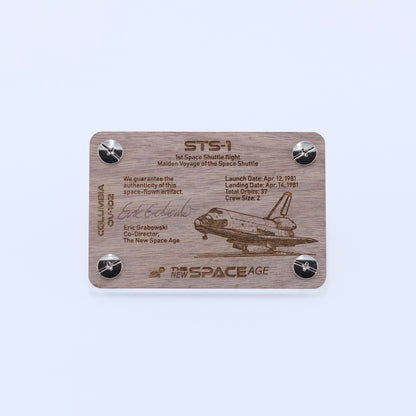 Back side of the STS-1 Columbia flown panel fragment artifact display card featuring mission details, authenticity statement, and Space Shuttle Columbia engraving.
