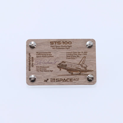 Back side of the STS-100 Endeavour flown payload bay liner artifact display card featuring mission details, authenticity statement, and Space Shuttle Endeavour engraving.
