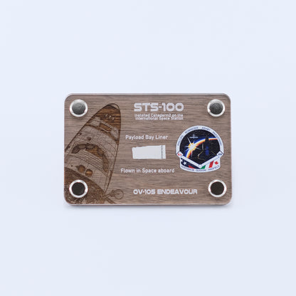 Authentic flown payload bay liner artifact from Space Shuttle Endeavour STS-100, the mission that installed Canadarm2 on the International Space Station, displayed in a handcrafted collectible card.