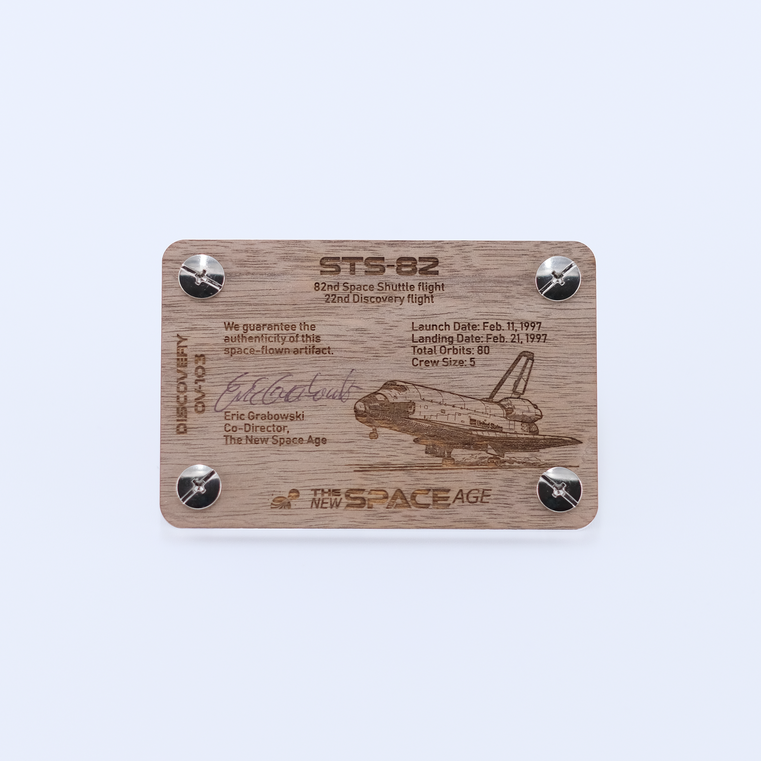 Back side of the STS-82 Discovery flown payload bay liner artifact display card featuring mission details, authenticity statement, and Space Shuttle Discovery engraving.