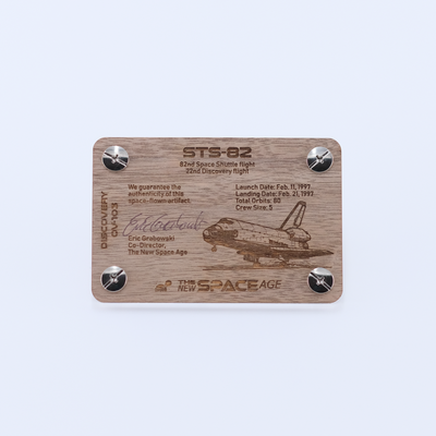Back side of the STS-82 Discovery flown payload bay liner artifact display card featuring mission details, authenticity statement, and Space Shuttle Discovery engraving.