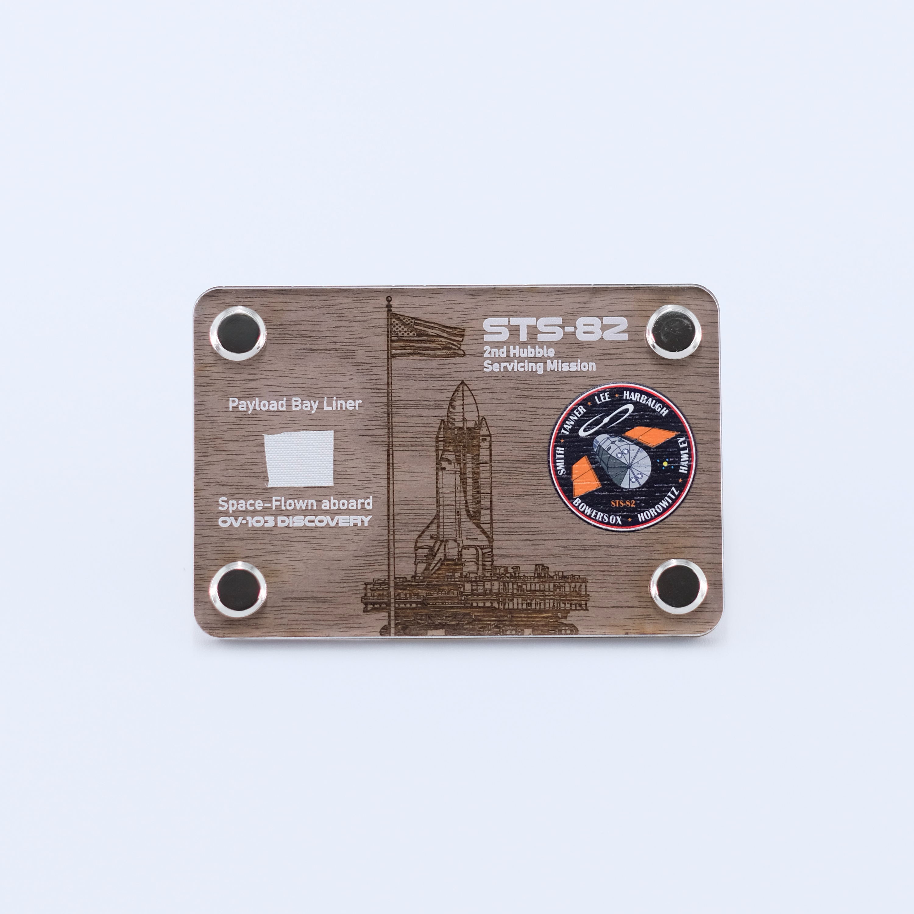 Authentic flown payload bay liner artifact from Space Shuttle Discovery STS-82, the second Hubble Space Telescope servicing mission, displayed in a handcrafted collectible card.