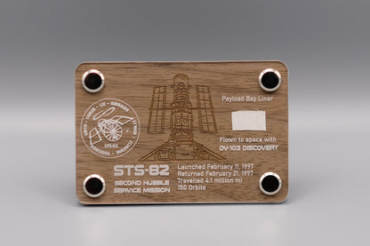 Wooden display with authentic flown Payload Bay Liner fragment from Space Shuttle Discovery STS-82 mission, engraved with Hubble Space Telescope servicing details.