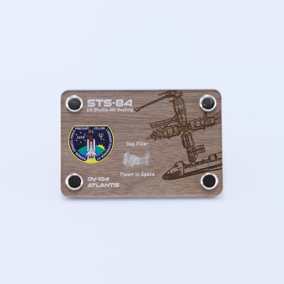 Authentic flown gap filler artifact from Space Shuttle Atlantis STS-84, the sixth Shuttle-Mir docking mission, displayed in a handcrafted collectible card.