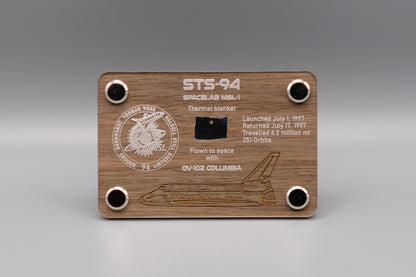Authentic flown thermal blanket fragment from Space Shuttle Columbia STS-94 (1997) mounted in engraved wooden display with mission patch and shuttle design