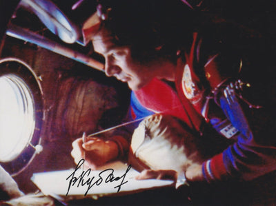 Signed photo of cosmonaut Valery Kubasov looking out of a Soyuz spacecraft window.