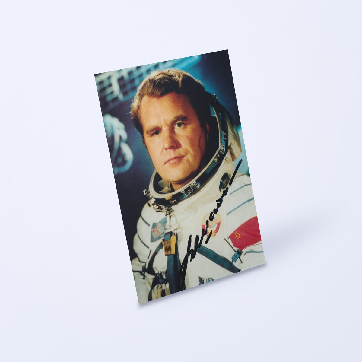 Signed portrait of cosmonaut Vladimir Shatalov in a Sokol spacesuit, shown at an angle on a light background